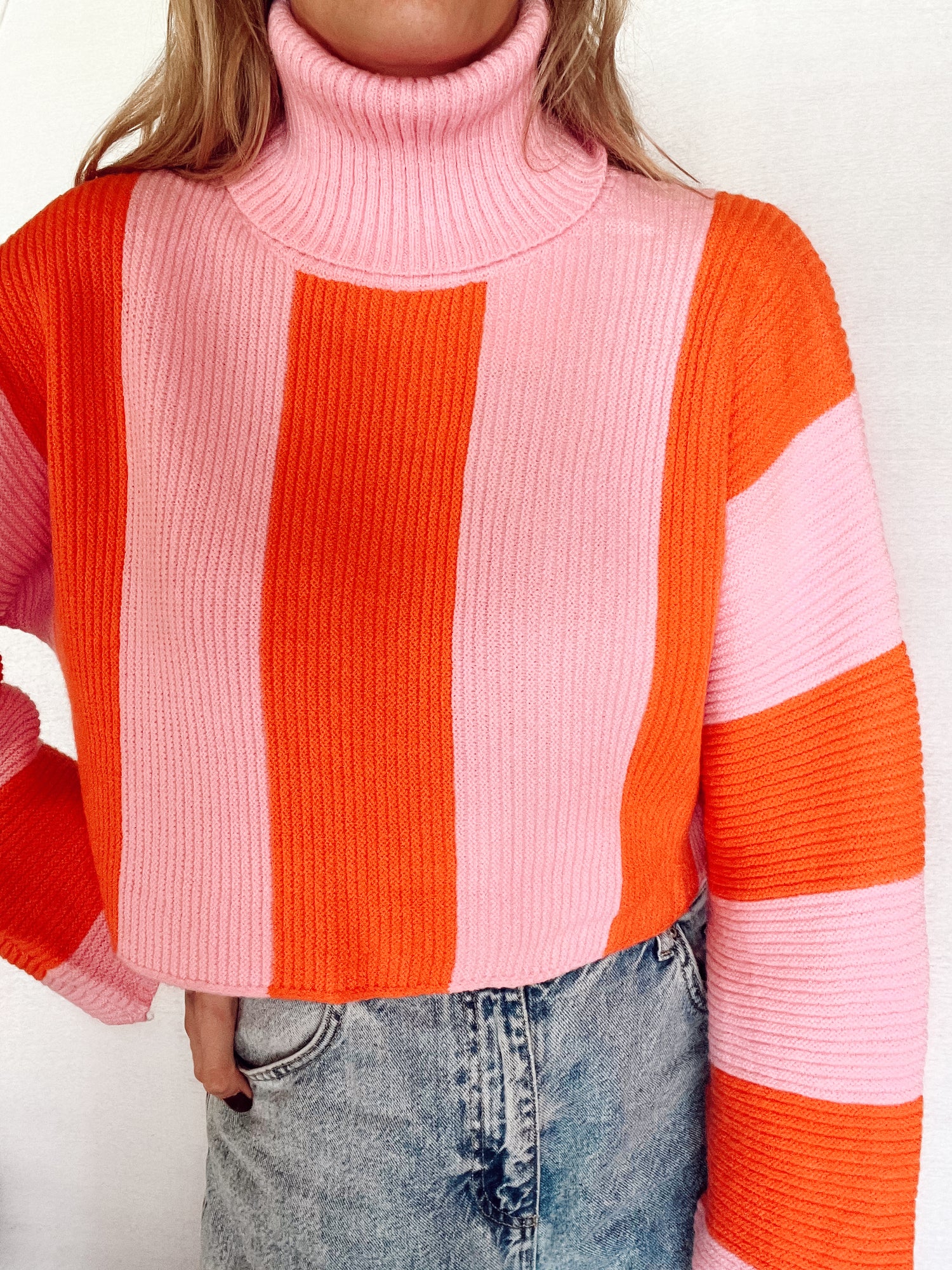 Roze oranje gestreepte sweater met col. De trui heeft een wat cropped model en wijd uitlopende mouwen. De trui is one-size en geschikt voor de maten S t/m L. Materiaal van de trui is: 50% viscose, 50% polyamide. Roze met oranje verticale strepen cropped trui