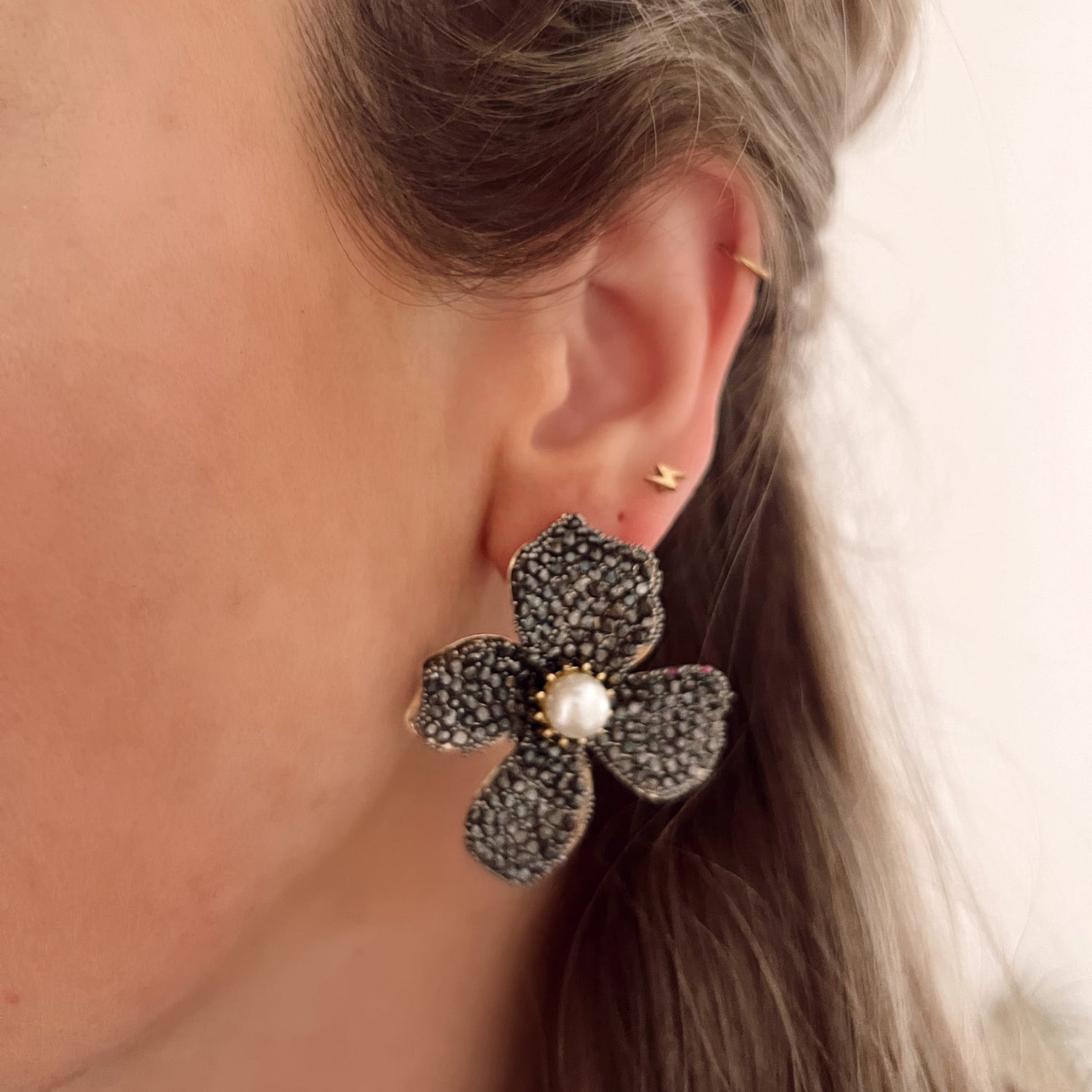 Zwarte statement oorbellen in de vorm van een bloem, ingelegd met steentjes. Afmetingen: 5 cm. Zwarte grote statement earrings bloem met steentjes. Grote oorbellen zwarte bloem.
