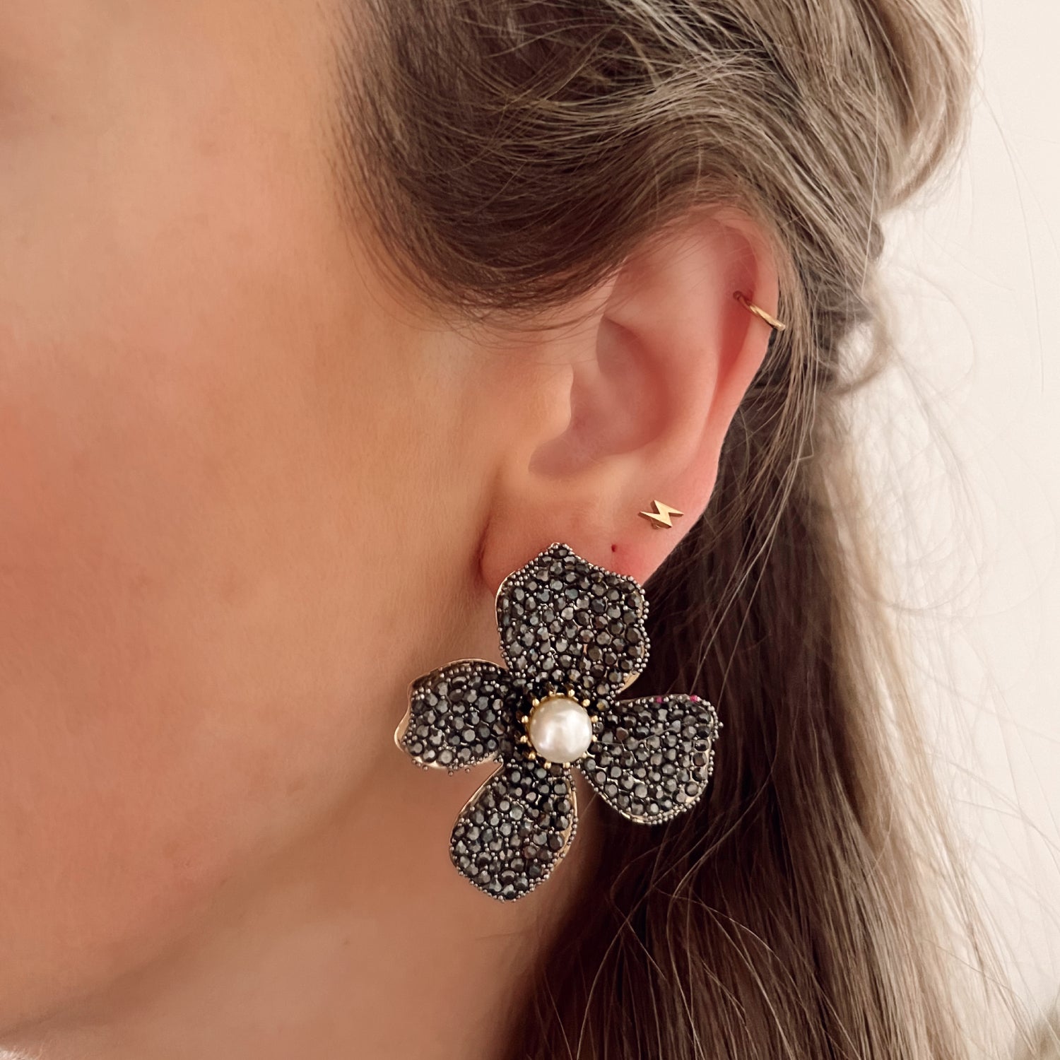 Zwarte statement oorbellen in de vorm van een bloem, ingelegd met steentjes. Afmetingen: 5 cm. Zwarte grote statement earrings bloem met steentjes. Grote oorbellen zwarte bloem.