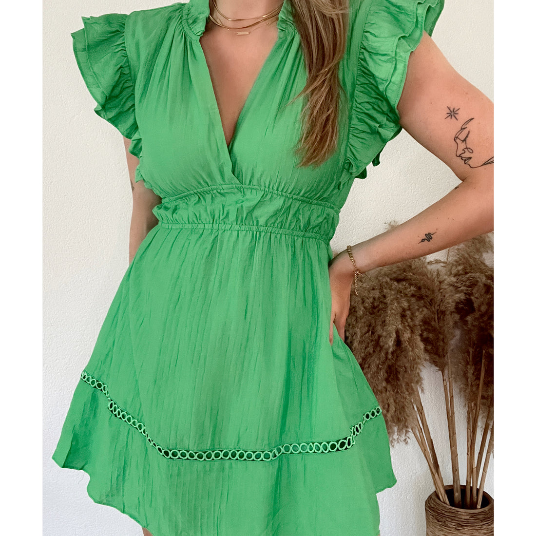 Groene katoenen jurk met ruffle mouwen en geborduurd detail aan de onderkant. De jurk heeft een elastiek in de taille waardoor het jurkje mooi valt. De jurk is van 100% katoen en valt normaal op maat. Groene katoenen jurk zonder mouwen met ruffle en broderie detail.