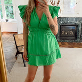 Groene katoenen jurk met ruffle mouwen en geborduurd detail aan de onderkant. De jurk heeft een elastiek in de taille waardoor het jurkje mooi valt. De jurk is van 100% katoen en valt normaal op maat. Groene katoenen jurk zonder mouwen met ruffle en broderie detail.
