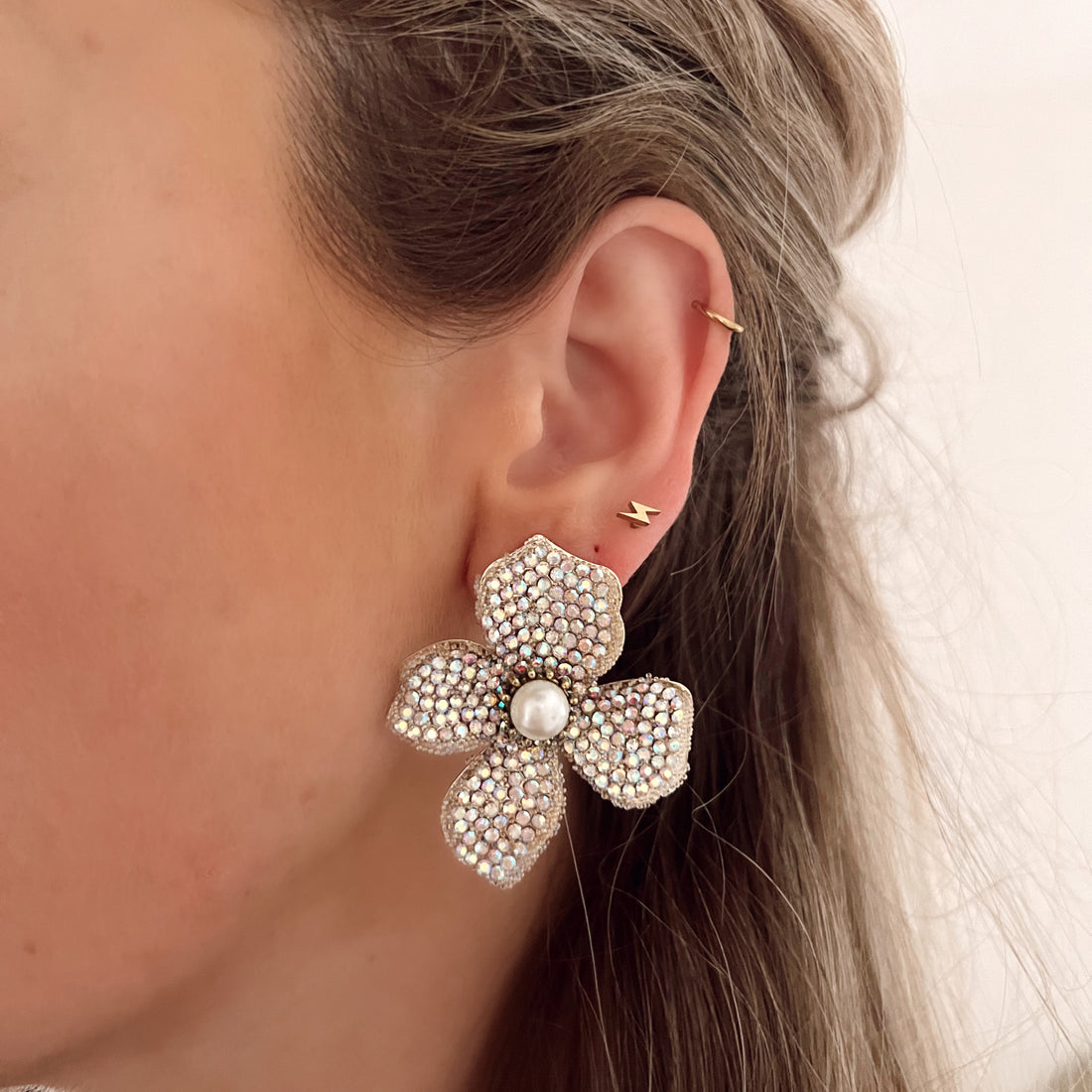 Witte statement oorbellen in de vorm van een bloem, ingelegd met steentjes. Afmetingen: 5 cm. Witte grote statement earrings bloem met steentjes. Grote oorbellen witte bloem.