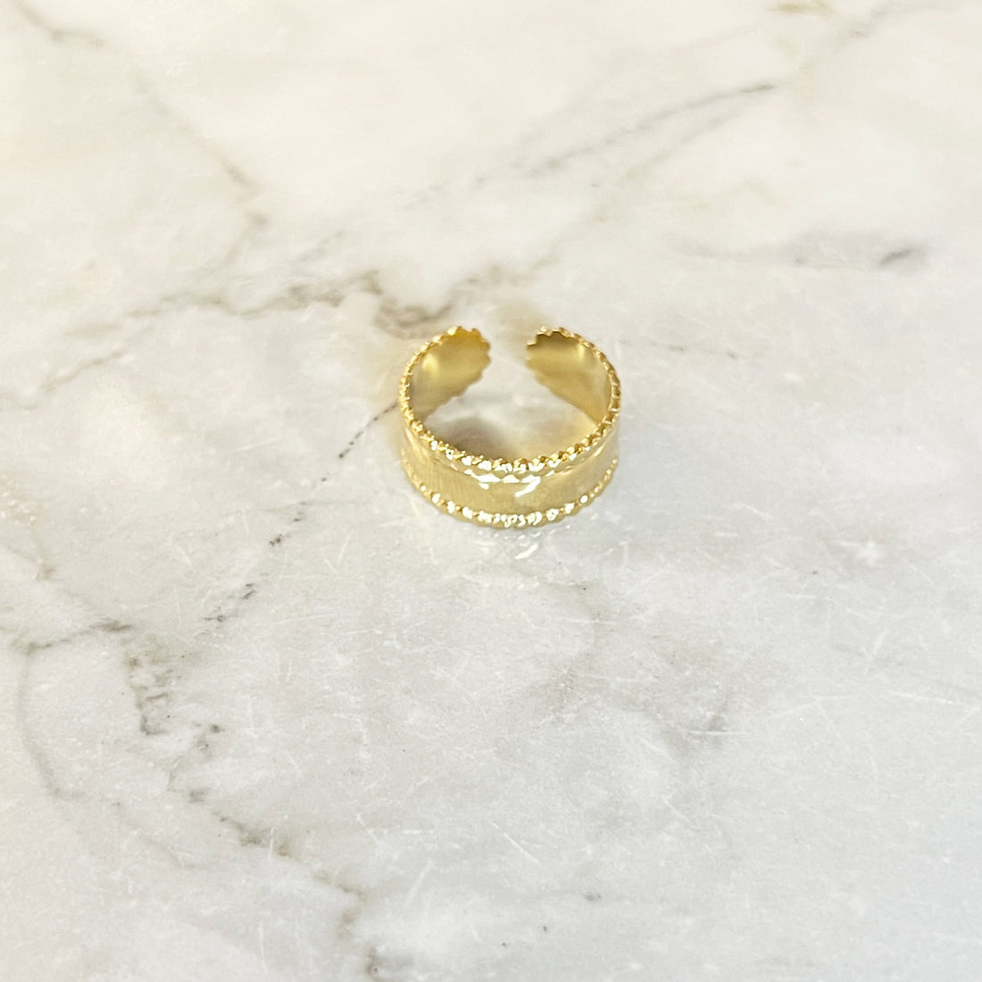 Gouden brede ring met gekartelde rand. De ring is van roestvrij staal met een gold plated laagje en is waterproof. De ring is one-size en verstelbaar.